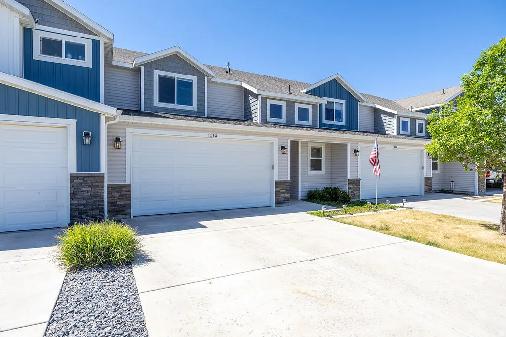 Contemporary townhome exterior featuring light blue vertical siding, gray horizontal siding, and dark stone veneer accents