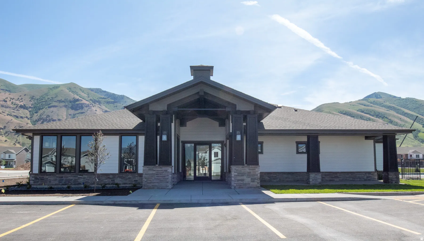 Contemporary facade with a prominent gabled entry, stone and siding exterior, large pane windows, and a surrounding mountain landscape