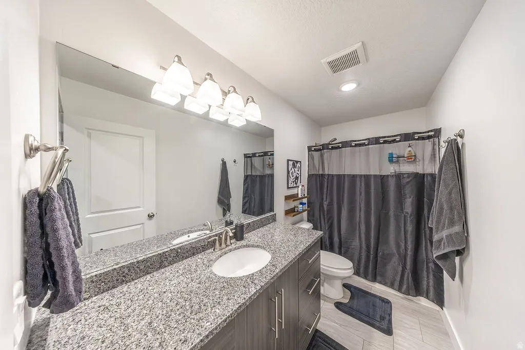 Bathroom featuring a spacious vanity with a light speckled countertop, an undermount sink, and a large wall-mounted mirror