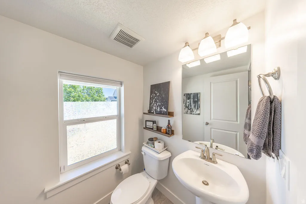 Pedestal sink with chrome faucet, large vanity mirror, and three-light fixture