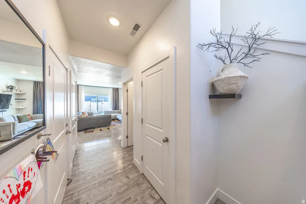 Hallway featuring wood-finish flooring, recessed lighting, and white paneled doors
