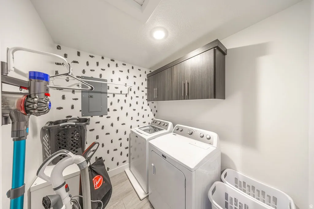Dedicated laundry space featuring a white top-load washer and dryer set, wood-finish upper cabinetry, and recessed lighting