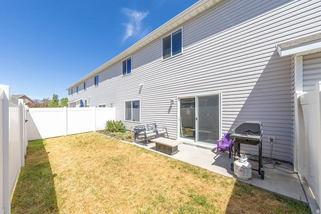 Private backyard featuring a concrete patio, sliding glass door entry, and full vinyl fencing
