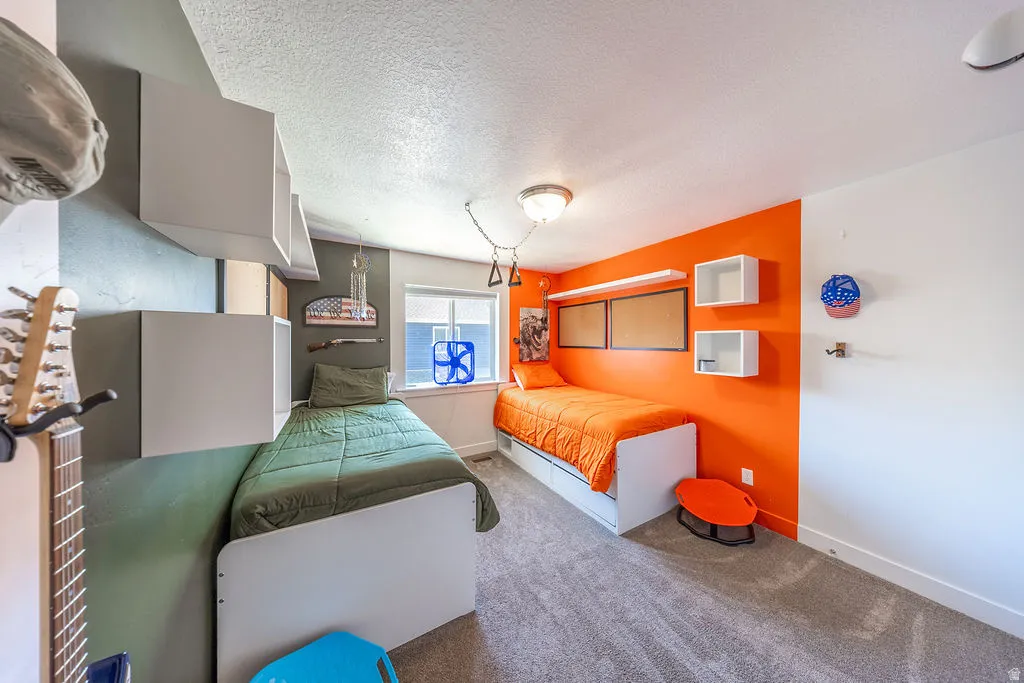 Bedroom featuring two single beds, built-in wall shelving, a window with blinds, and carpeted flooring