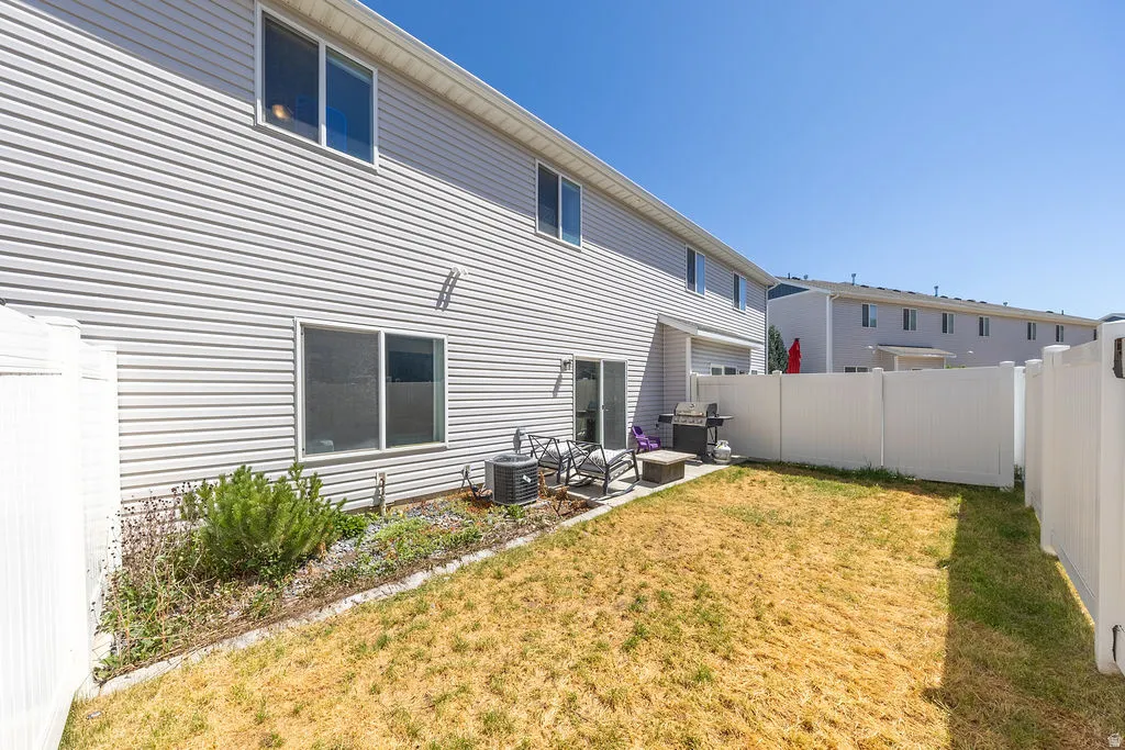 Fenced backyard featuring a sliding glass patio door, ground-level patio, and vinyl siding exterior