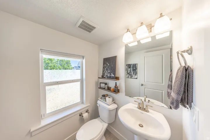 Pedestal sink with chrome faucet, large vanity mirror, and three-light fixture