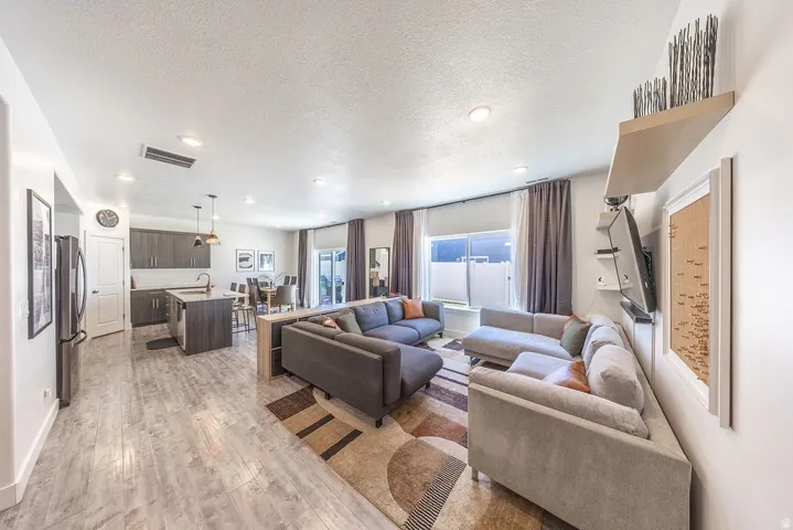 Open-concept living area featuring wood-finish flooring, recessed lighting, and a modern kitchen with dark cabinetry