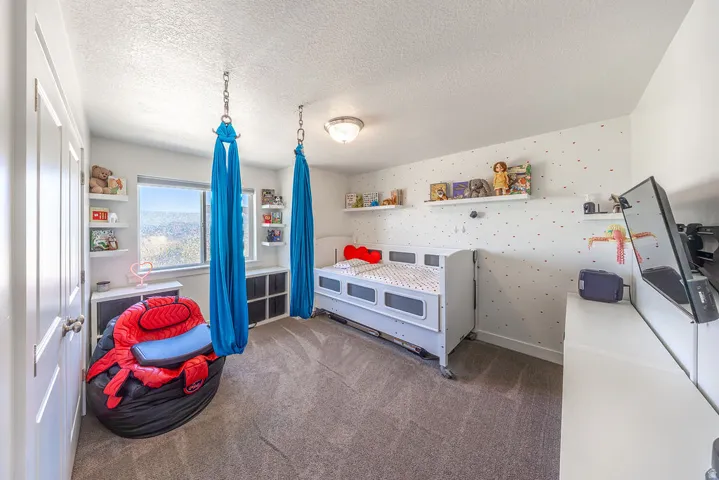 White interior walls with a patterned accent wall, light-colored carpet flooring, recessed lighting, and a window with outdoor scenery
