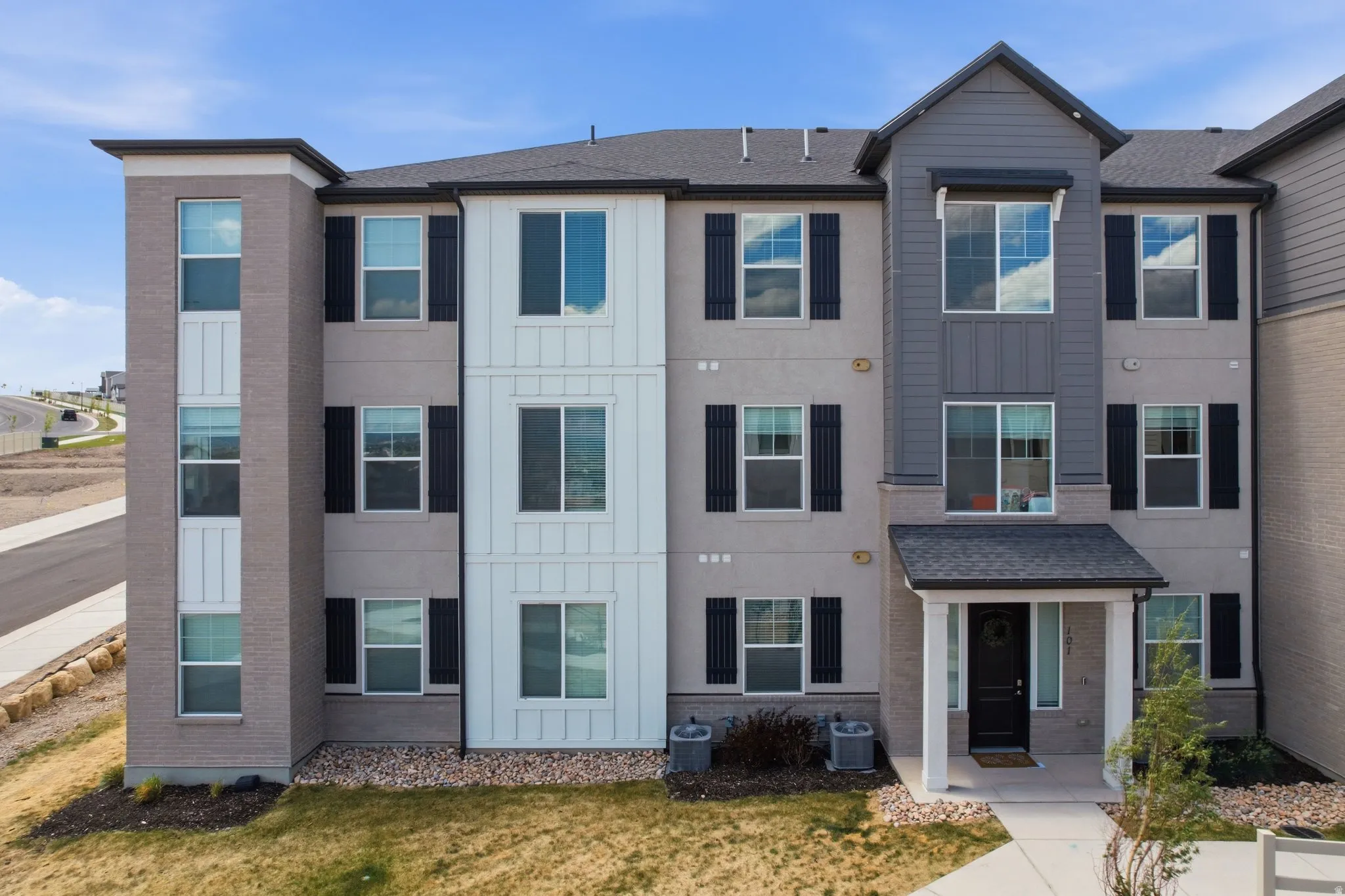 Modern multi-level townhome featuring a dark gray roofline and contrasting exterior finishes