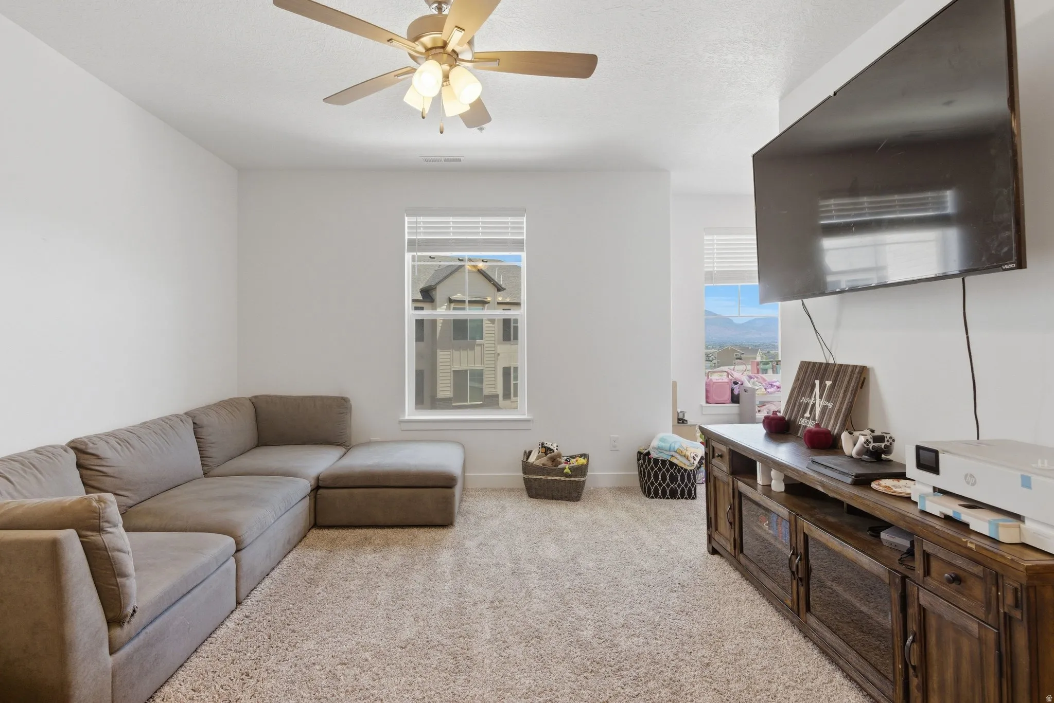 Spacious room with light-colored carpet flooring, a ceiling fan with integrated lighting, and white walls