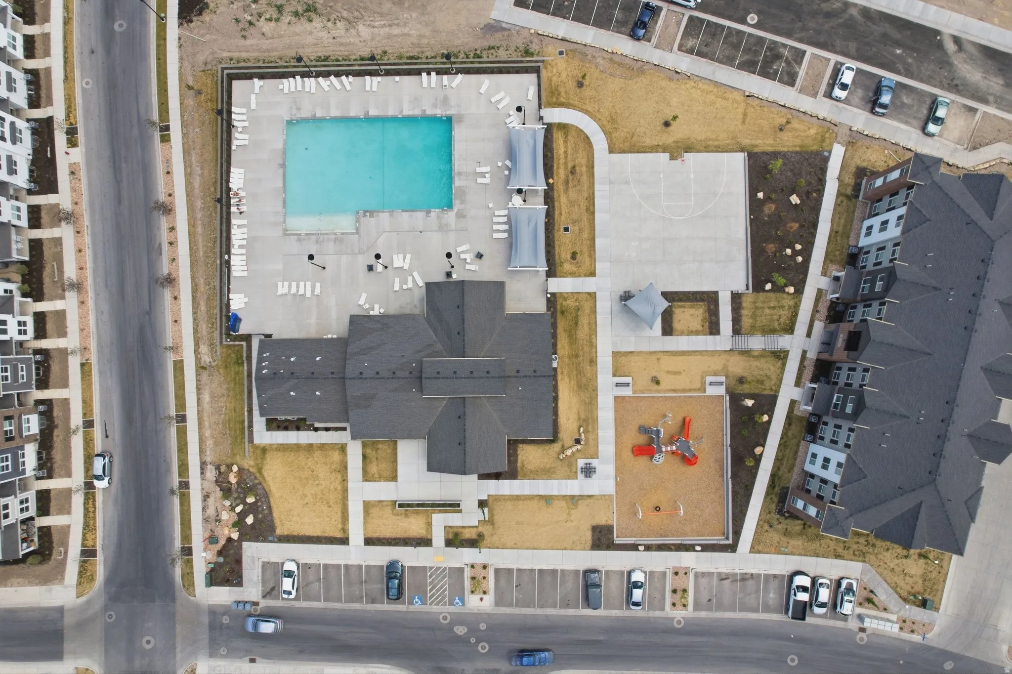 Community amenities featuring a rectangular swimming pool with surrounding lounge seating, a basketball court, and a playground area with a shade structure