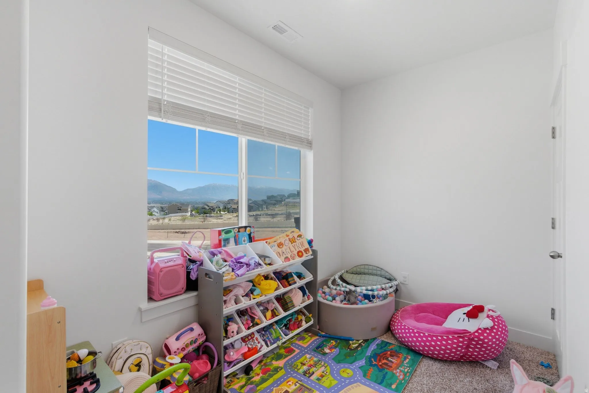 Bright room featuring a large window with horizontal blinds, showcasing distant mountain scenery