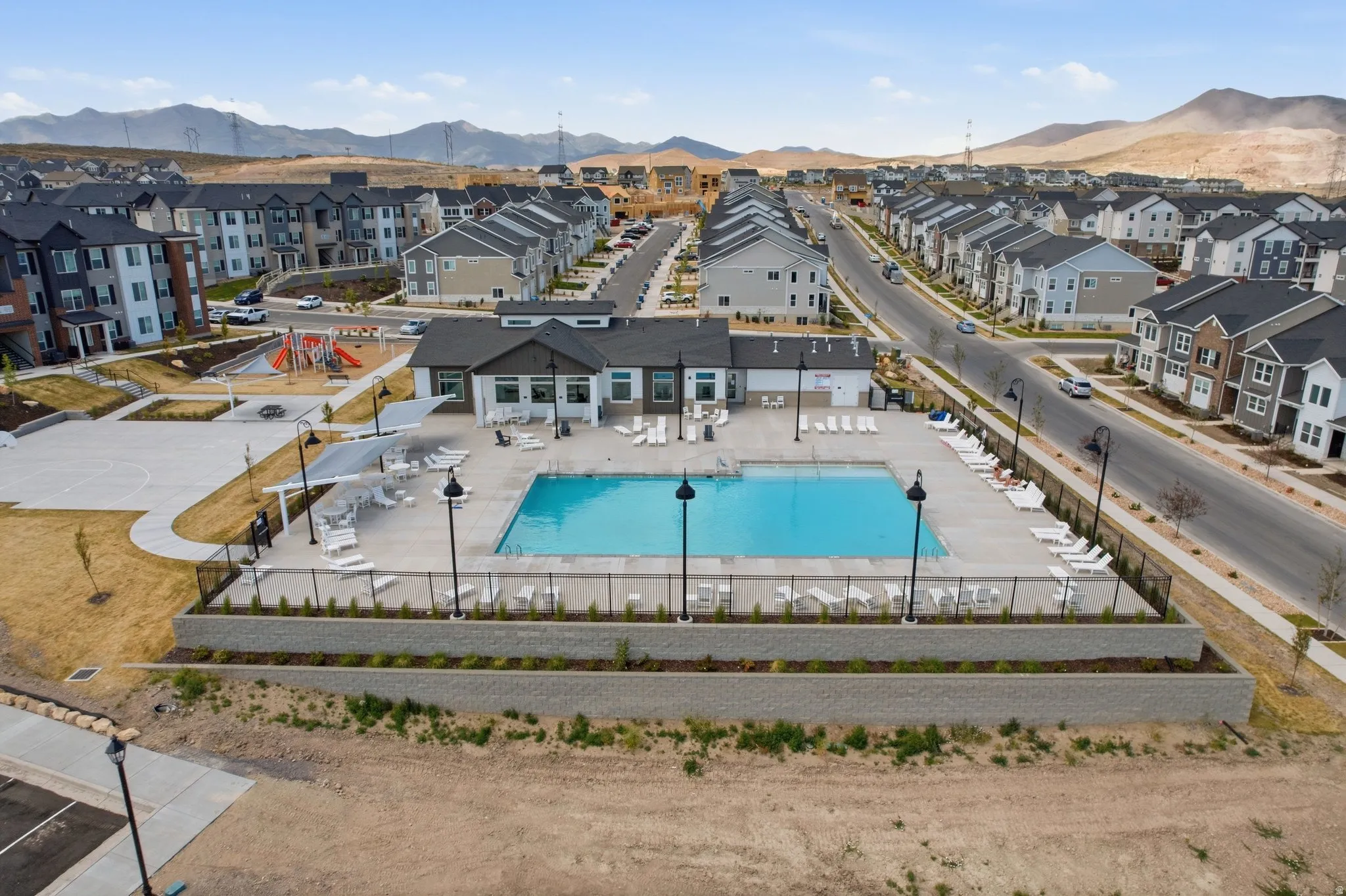 Community amenities featuring a central swimming pool, integrated clubhouse, sun loungers, and black metal fencing