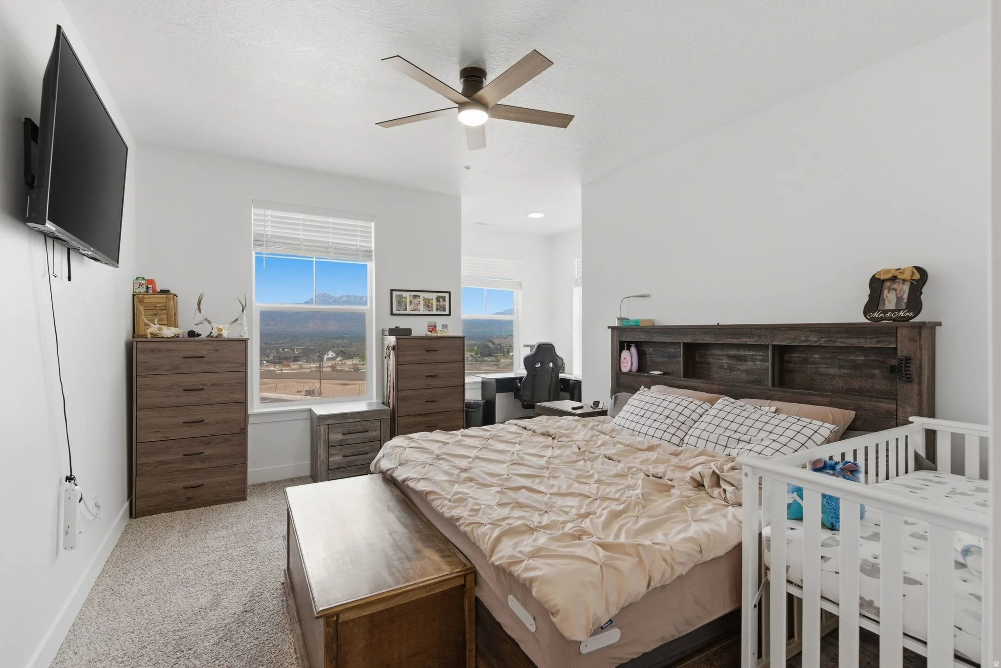 Carpeted room featuring multiple windows with mountain scenery, a ceiling fan, and white walls