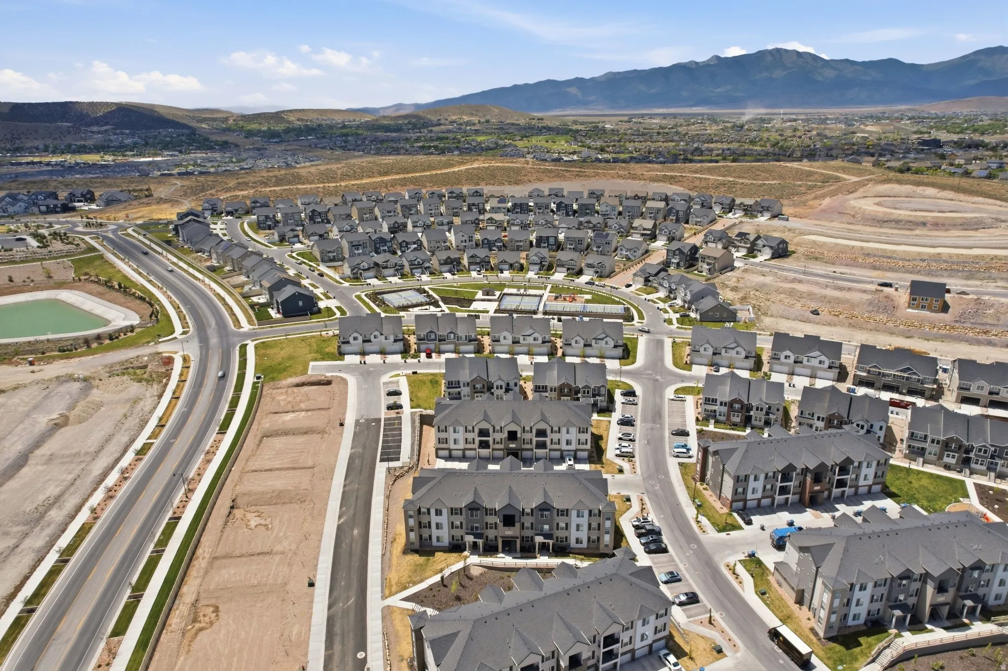 Aerial perspective of a developing residential community, featuring a mix of single-family homes and multi-story apartment buildings