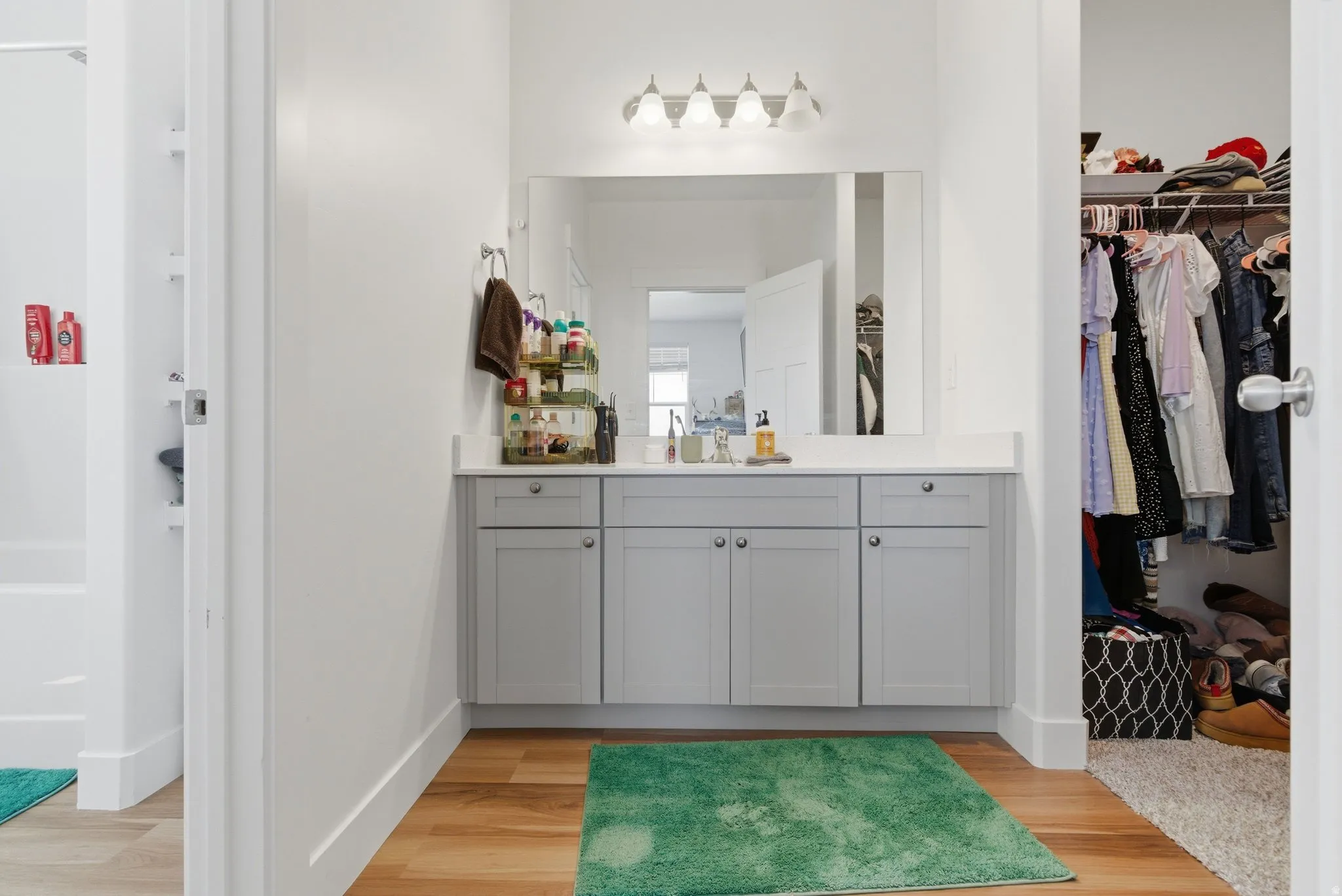 Bathroom vanity with a light gray cabinet base, white countertop, and a large mirror