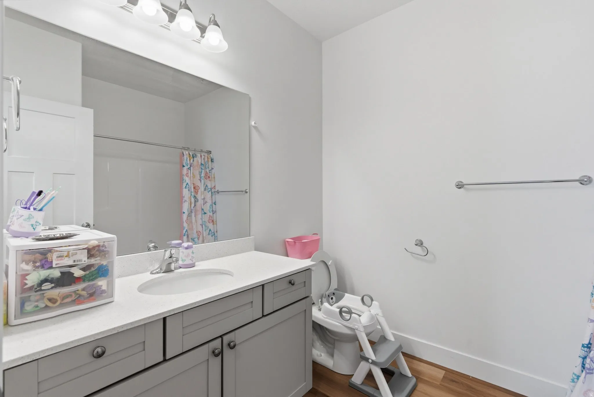 Bathroom vanity with light gray cabinetry, a white countertop, and an integrated sink
