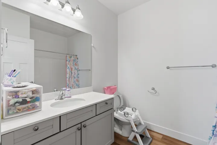 Bathroom vanity with light gray cabinetry, a white countertop, and an integrated sink