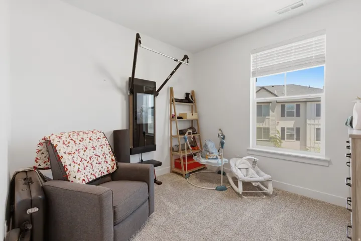 Bright room with a large window, neutral wall paint, light-colored carpet, and white window blinds