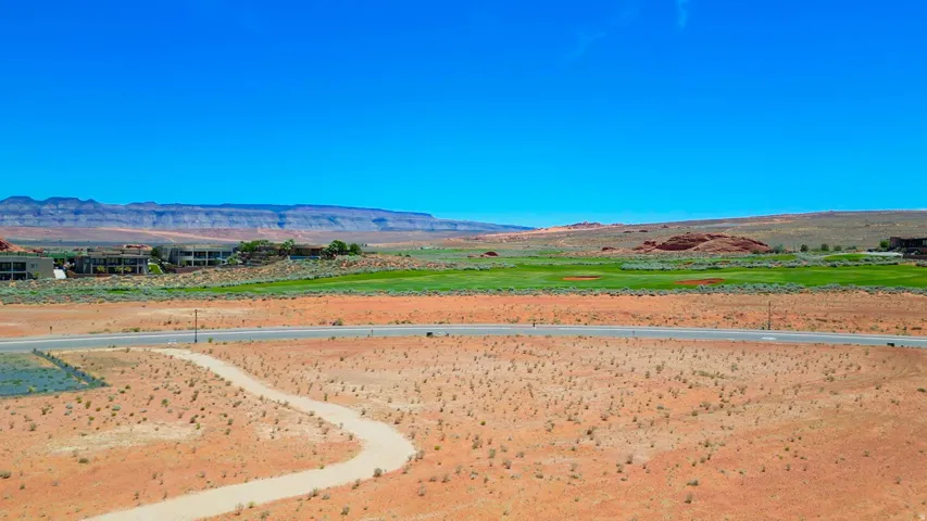 Expansive desert landscape featuring a paved roadway and a winding path