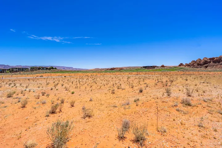 Expansive desert landscape featuring natural rock formations and distant structures under a clear sky