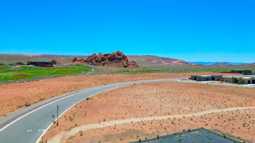Expansive desert landscape featuring red rock formations and a distant golf course