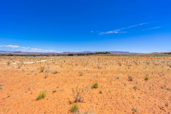 Expansive desert landscape featuring reddish-orange earth and sparse vegetation