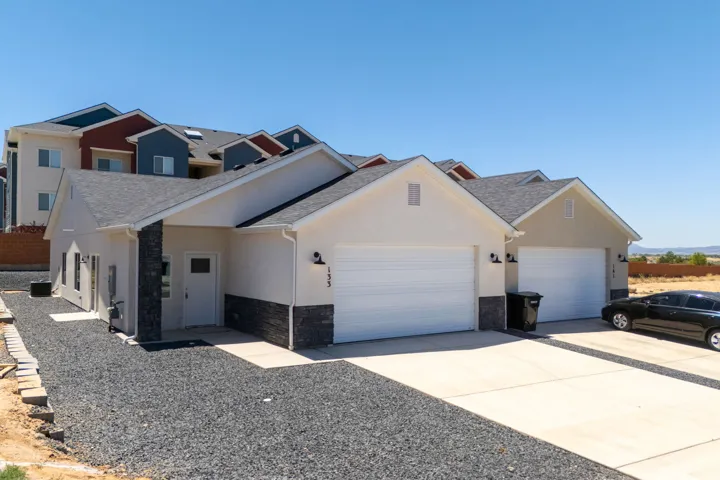 Stucco exterior featuring stacked stone accents, a covered front entry, and an attached two-car garage