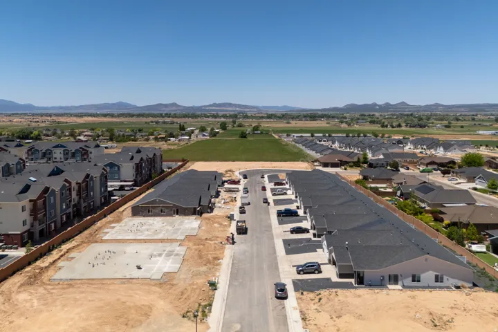 Aerial perspective showcasing a developing residential community featuring new construction with asphalt shingle roofs and concrete foundations laid