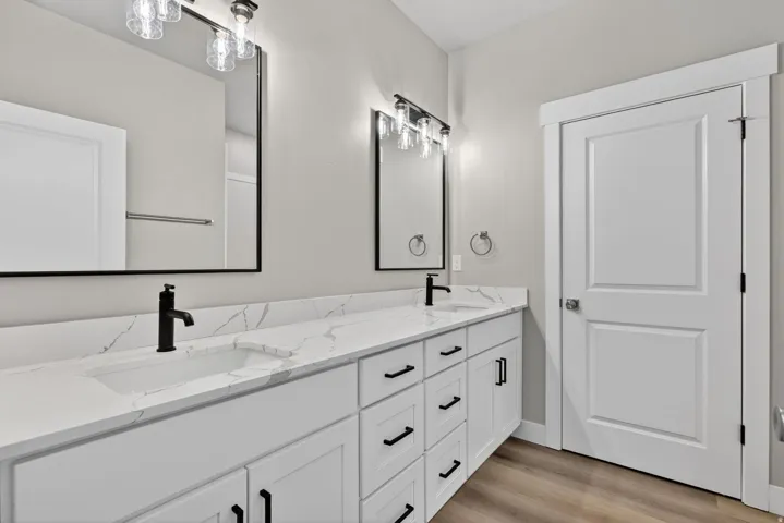 Dual vanity featuring quartz countertops, undermount sinks, and matte black fixtures