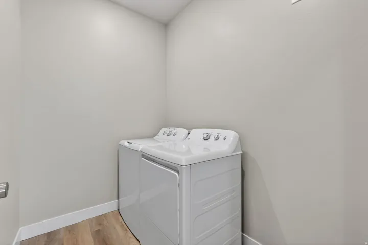Dedicated utility area featuring wood-finish flooring, light neutral wall tones, and white baseboards