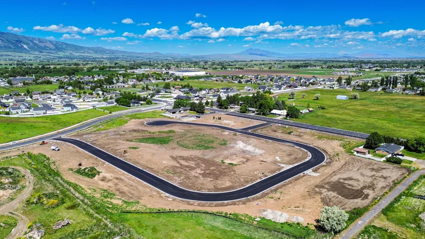 Developed land with new asphalt roadways, mountain scenery, surrounding green fields, and established residential areas