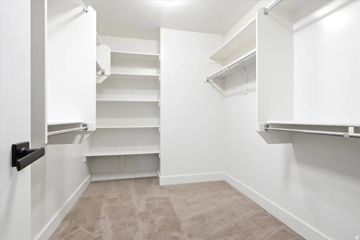 Walk-in closet featuring built-in shelving, multiple hanging rods, and neutral carpet flooring