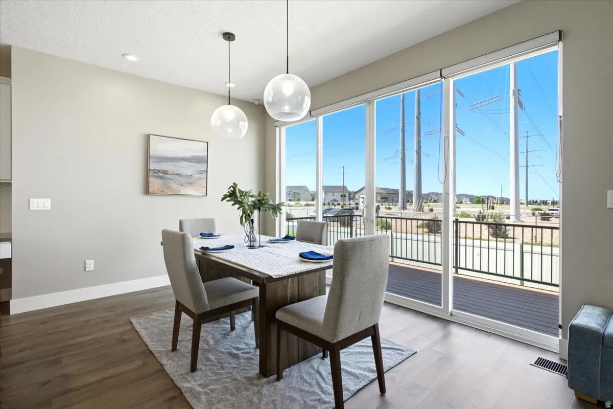 Dining space featuring wood-finish flooring, two modern pendant lights, recessed ceiling lighting, and a neutral wall color