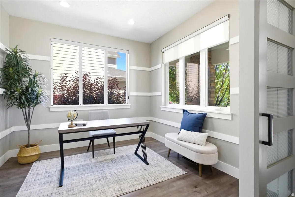 Bright room featuring multiple windows, recessed lighting, wood-finish flooring, and a modern interior door with frosted panels