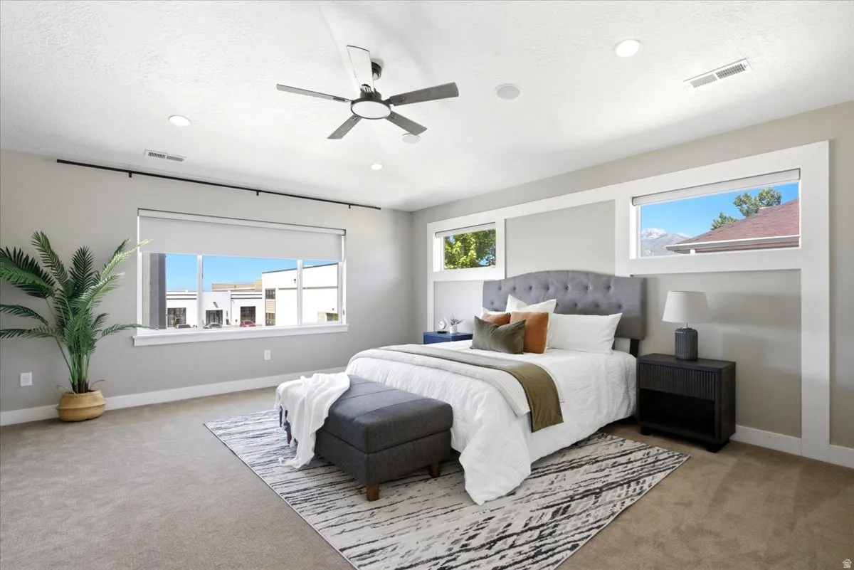 Spacious bedroom featuring light neutral walls, recessed lighting, and a ceiling fan