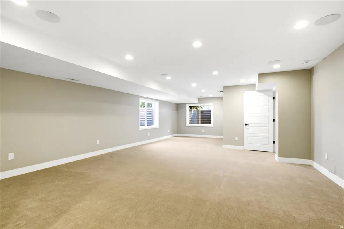 Spacious room featuring neutral carpeting, recessed lighting, and white trim