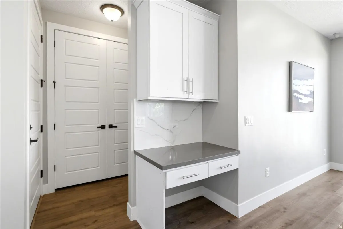 Integrated desk area featuring a gray countertop and white cabinetry