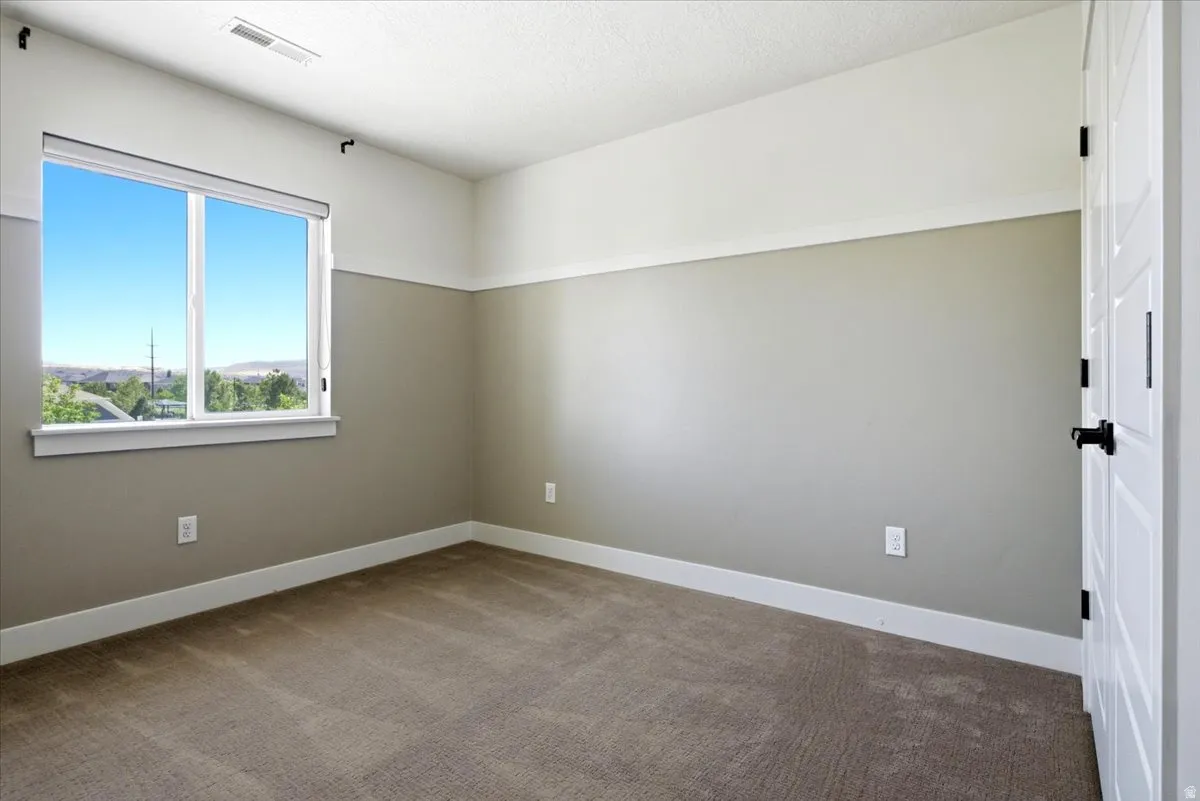 Room featuring textured carpeting, white baseboards, and a two-tone wall treatment