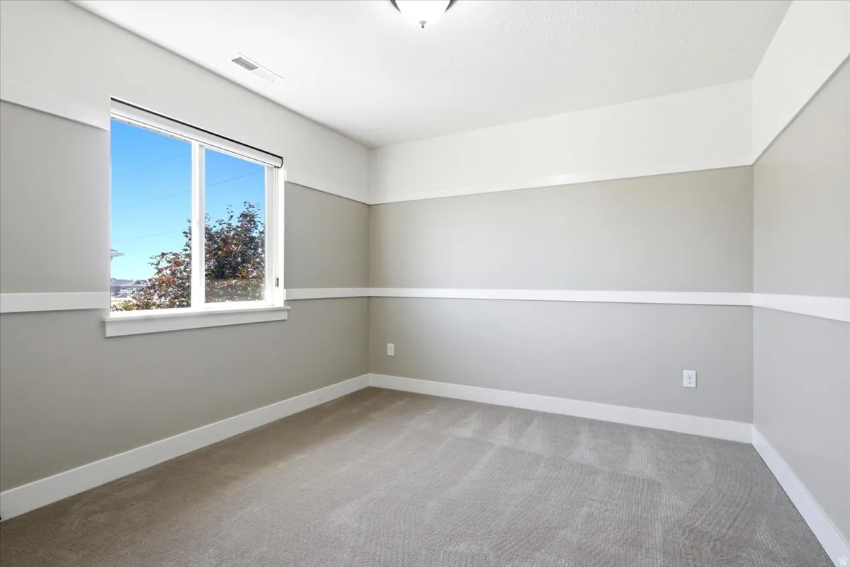 Spacious room featuring neutral carpeting and a large window with white trim