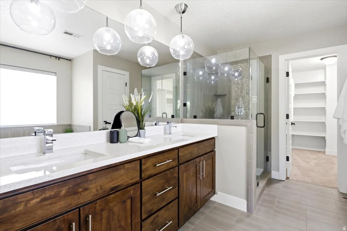 Bathroom featuring a dual vanity with wood-finish cabinetry, white countertops, and undermount sinks