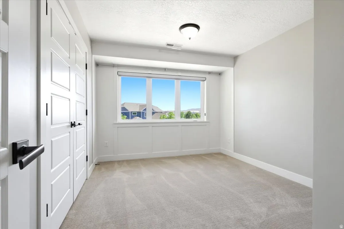 Bright room featuring a large window, neutral carpeting, and a flush mount ceiling light