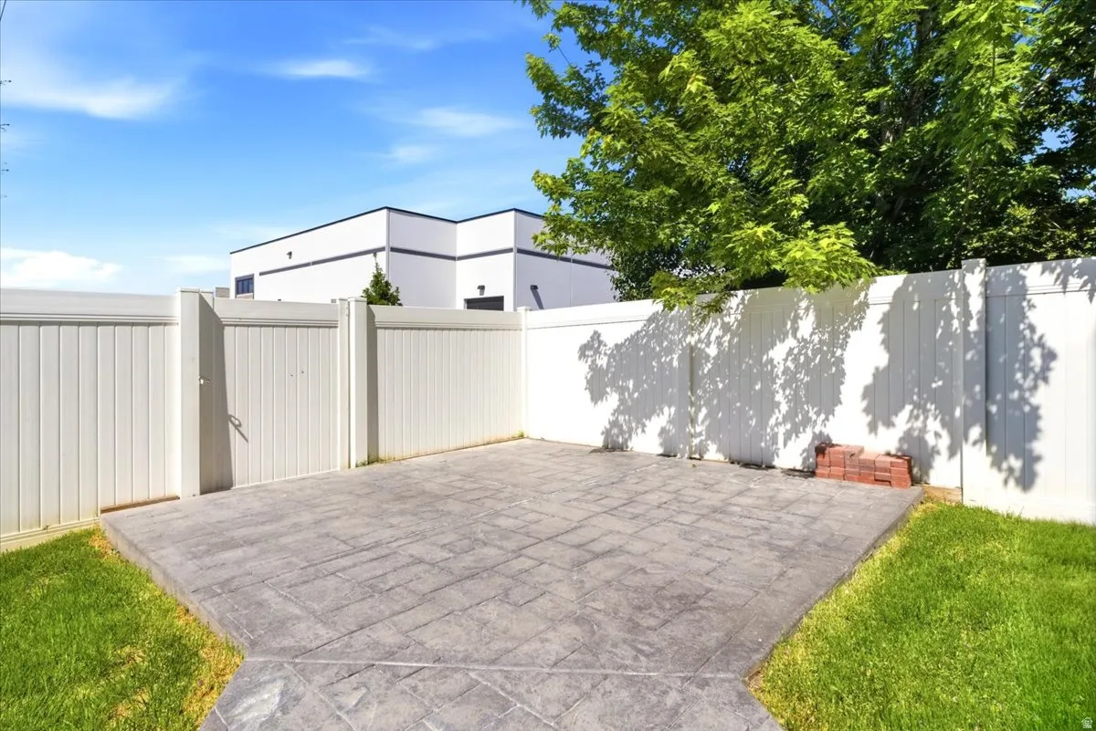 Patio area featuring stamped concrete, a white vinyl privacy fence, and a white vinyl gate