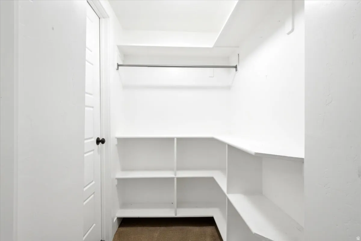 Walk-in closet featuring white built-in shelving, a garment rod, and a privacy door with a black knob