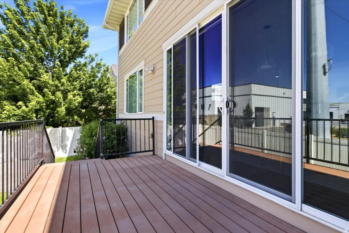 Spacious outdoor deck featuring composite decking, black metal railings, and a large sliding glass door with an integrated screen door