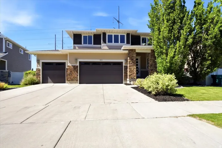 Contemporary exterior featuring a split-level design, a two-car garage, a single-car garage, stone veneer accents, and a concrete driveway
