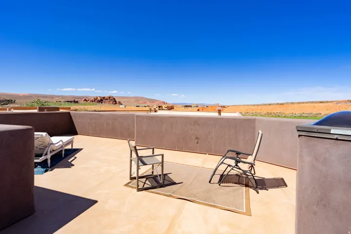 Expansive outdoor patio with concrete flooring, stucco wall surrounds, and distant natural landscape