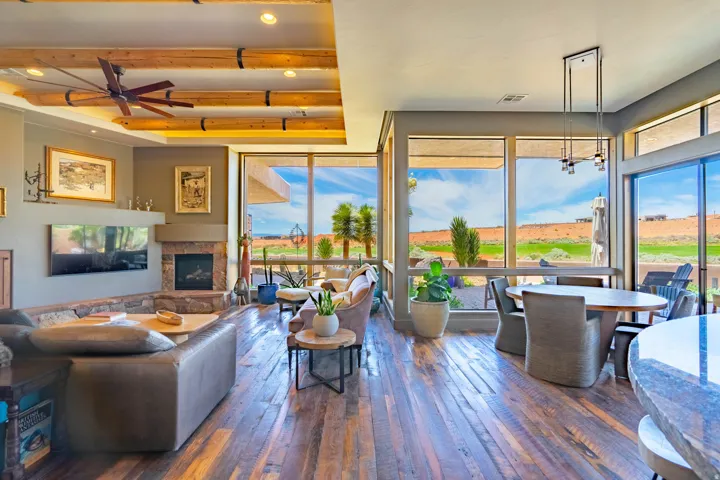 Spacious living area featuring wood-finish flooring, a stone fireplace, and exposed beam ceilings