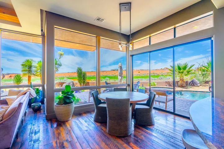Dining area featuring expansive windows, wood-finish flooring, a contemporary chandelier, and direct access to an outdoor patio with a swimming pool