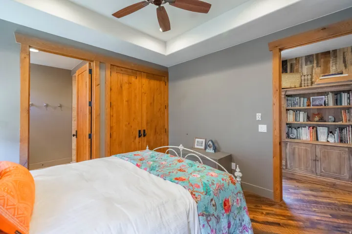 Interior room featuring a tray ceiling, wood-finish flooring, and a ceiling fan